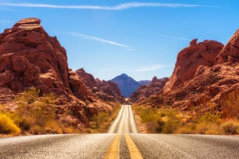 A road extends into the distance through a desert landscape