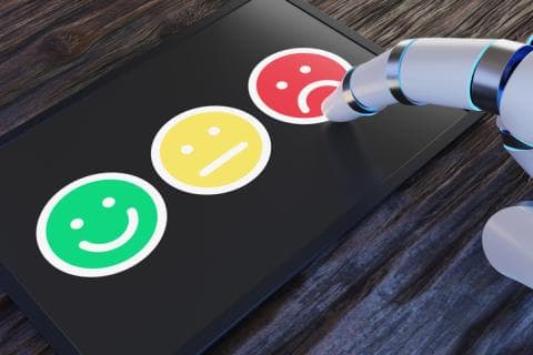 A robot hand takes a survey using emoji faces